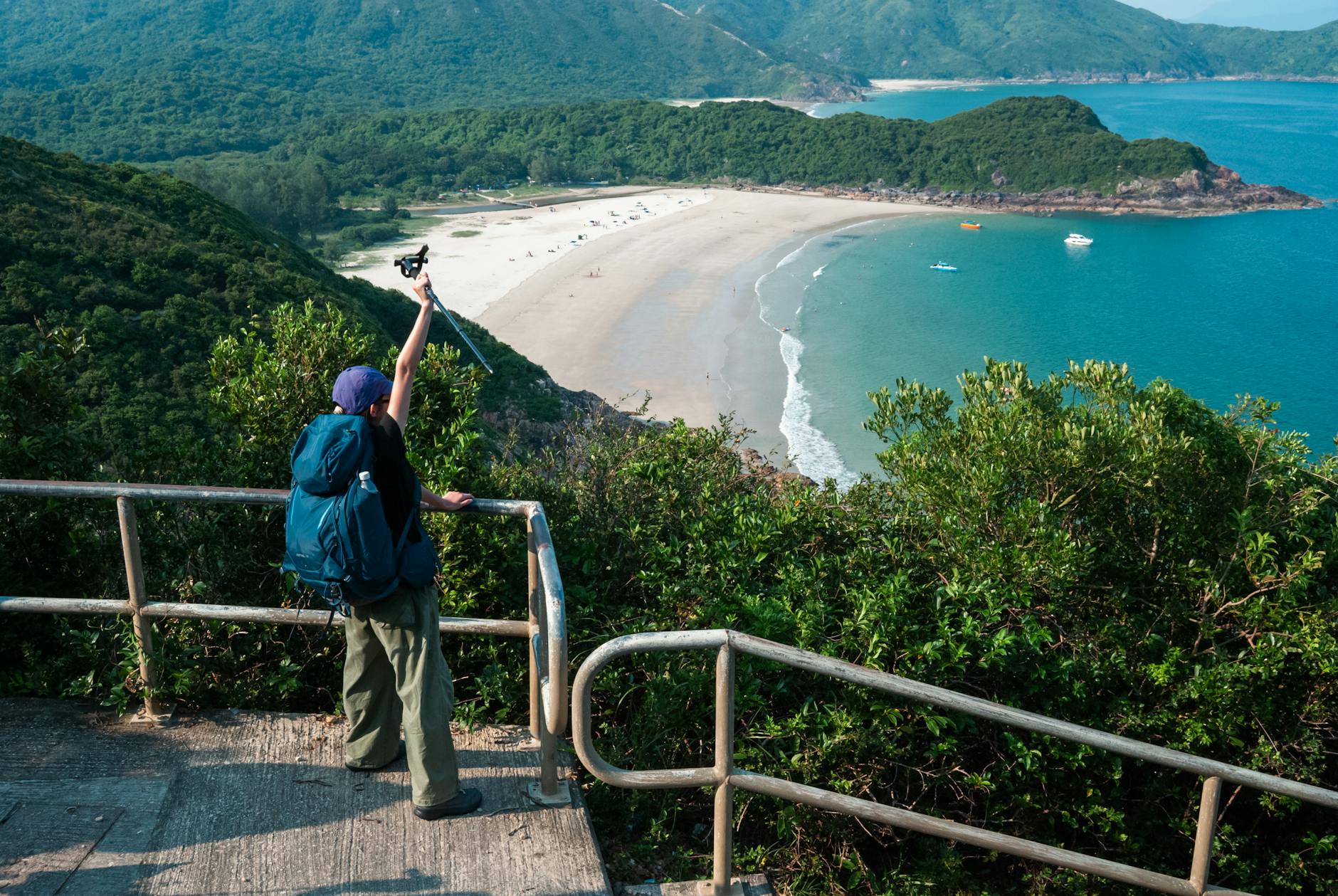 Turysta z plecakiem fotografuje nadmorski szlak z punktu widokowego w Hongkongu