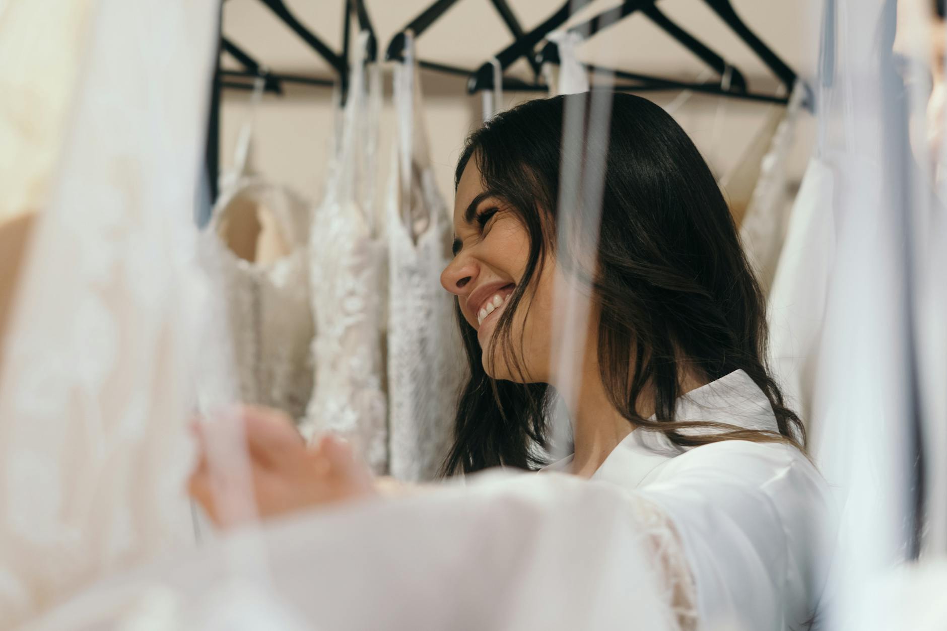 Uśmiechnięta panna młoda mierzy suknię ślubną w salonie bridal