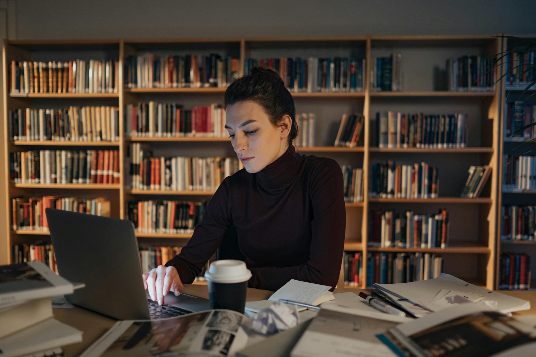 Kobieta po pracy uczy się przy laptopie w cichej bibliotece